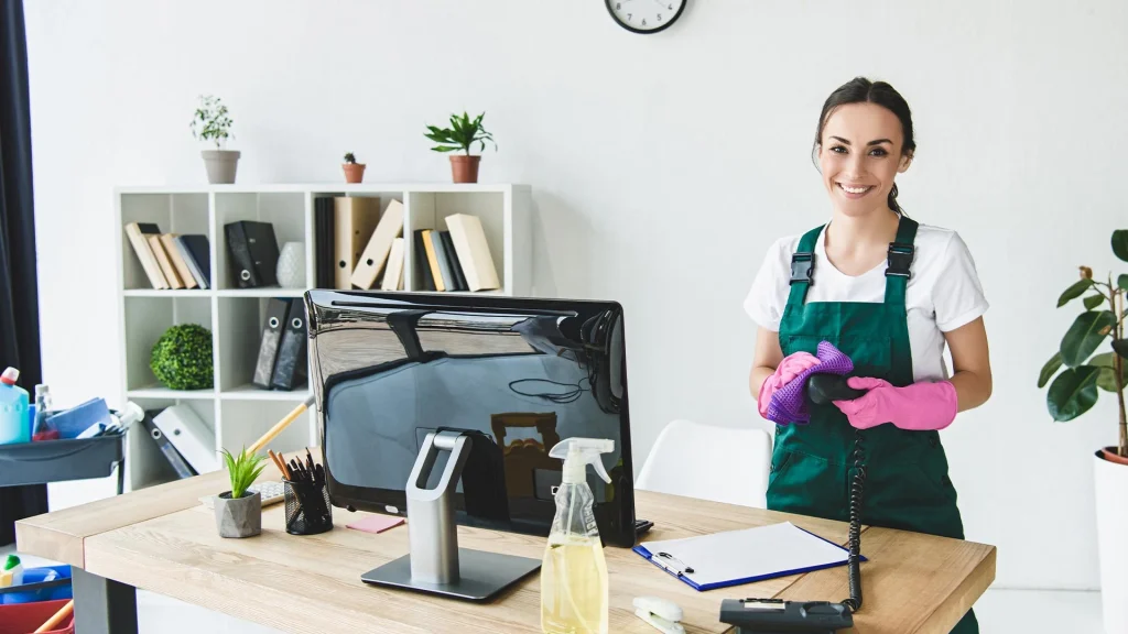 Reinigungskraft wischt Schreibtisch in modernem Büro